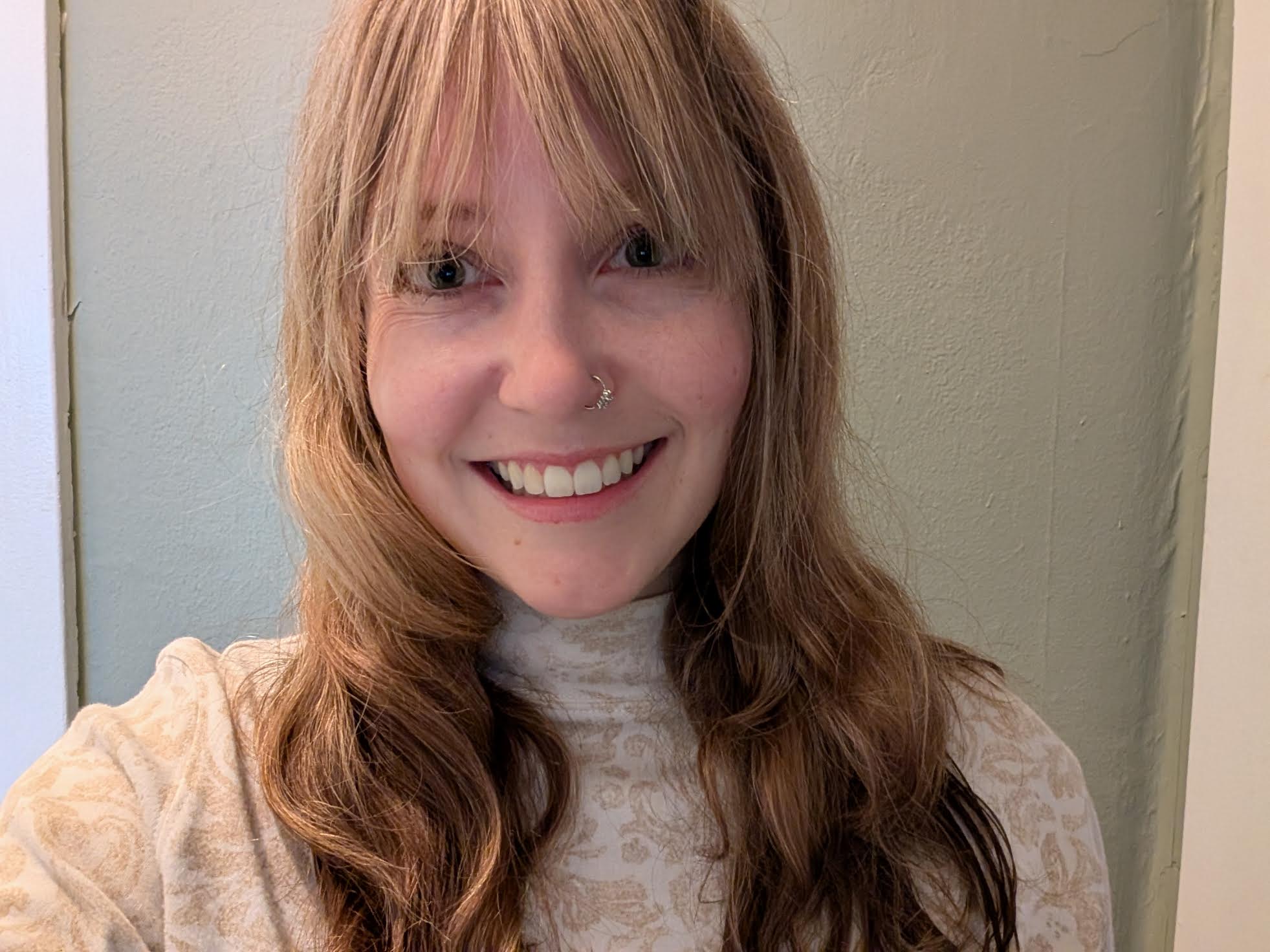 A headshot of Julianne Reese, she is smiling warmly with a white turtle-neck shirt
